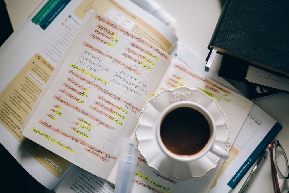 A translator's desk with a Korean novel open beside a laptop, handwritten notes and dictionaries, warm natural light