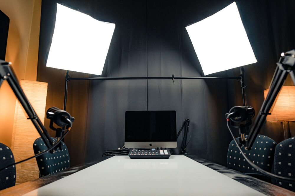 Empty radio broadcast studio at night with microphone, mixing console and glowing screens, no presenter