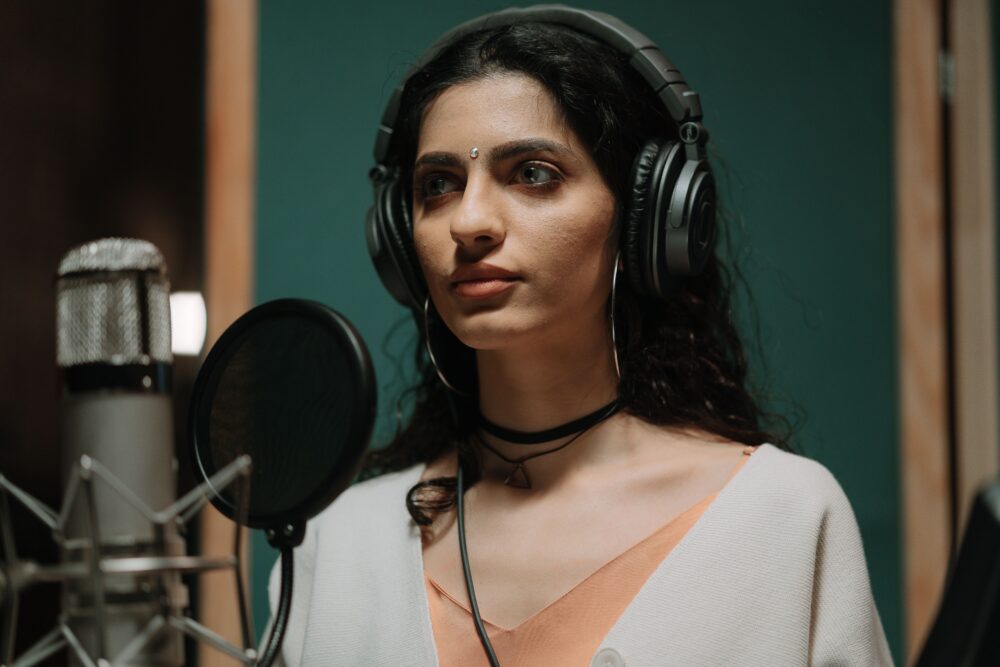 Indian playback singer recording vocals in a professional studio, microphone and headphones, warm lighting