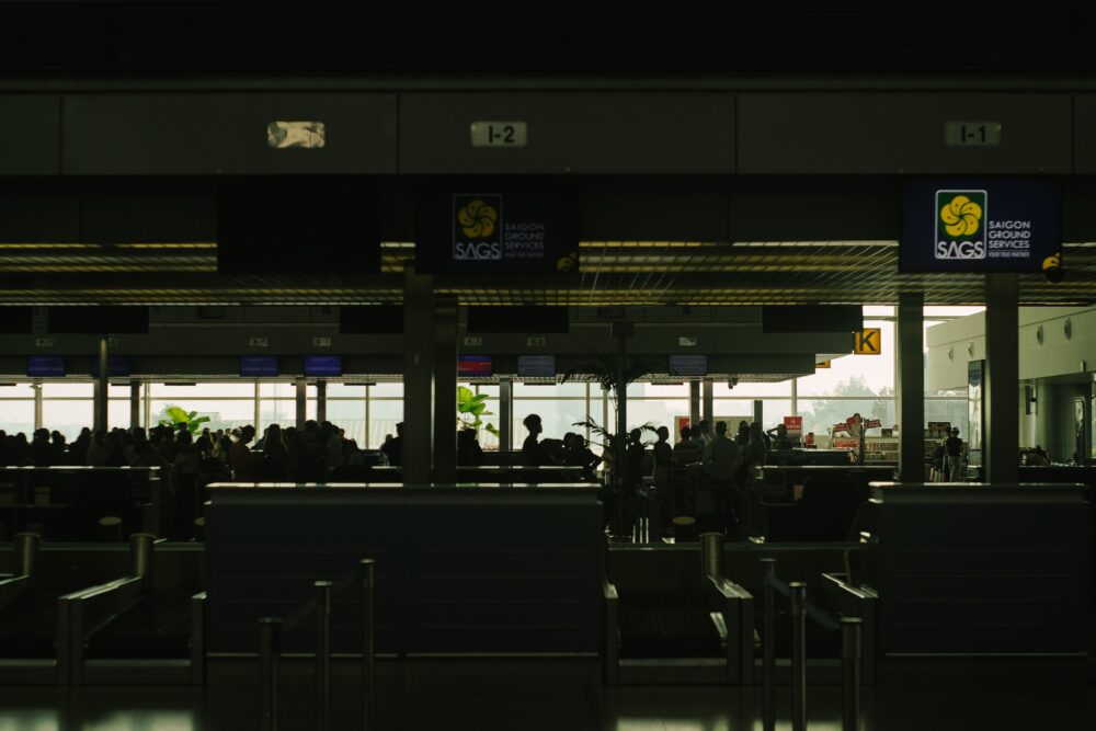 Airport check-in counter with an airline customer service desk, blurred travelers in the background, modern terminal