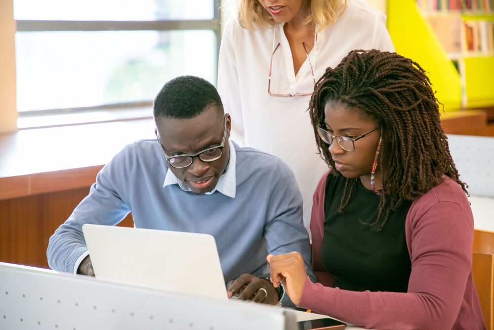 African researchers working together at a laptop during a machine learning workshop, collaborative annotation...