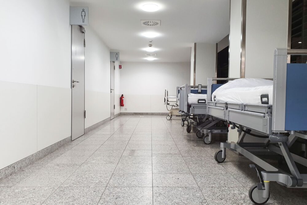 Empty hospital emergency department waiting room with rows of chairs and a reception desk, cold winter light, United...
