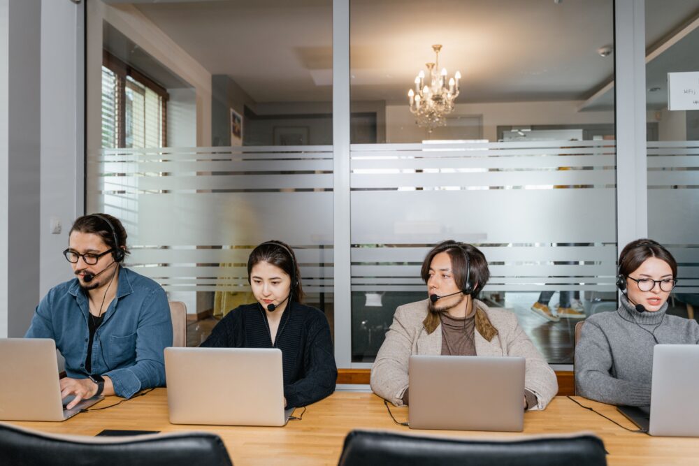 Call center workers wearing headsets at computer workstations in a large modern open-plan office in Manila, Philippines